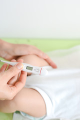 Obraz na płótnie Canvas Checking baby temperature which indicates high fever on thermometer