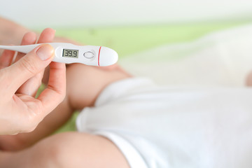 Checking baby temperature which indicates high fever on thermometer