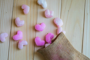 Pink hearts spill from sack on wooden background