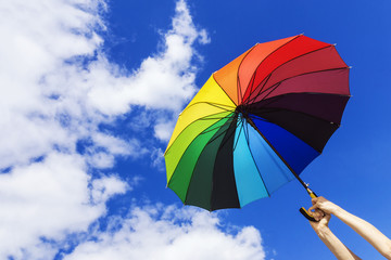 multicolored umbrella in hand on background sky