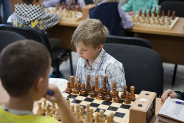 Little clever boy thinking about chess