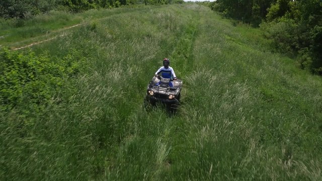 Young man driving quadbike in the forest.
