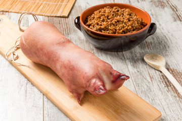 Zampone crudo sul tagliere di legno con lenticchie cotte nel coccio  su un tavolo 