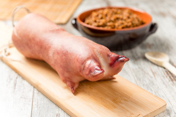 Zampone crudo sul tagliere di legno con lenticchie cotte nel coccio  su un tavolo 
