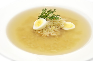 broth with pasta greens and quail egg in a white plate