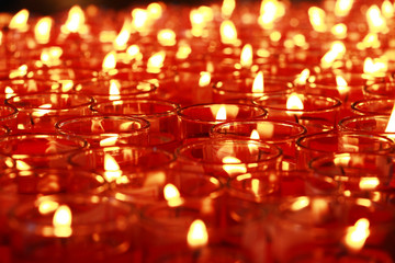 Many red candles burning at Buddhist temple interior