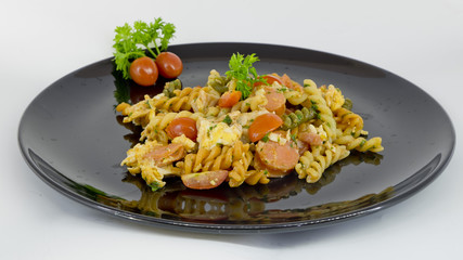 Macaroni pasta with tomato sauce and sausage on a black and whit