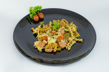 Macaroni pasta with tomato sauce and sausage on a black and whit