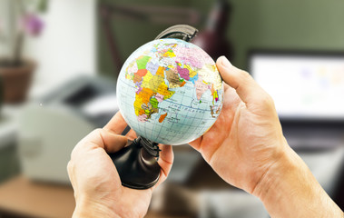 globe in the hands on the background blurred office background