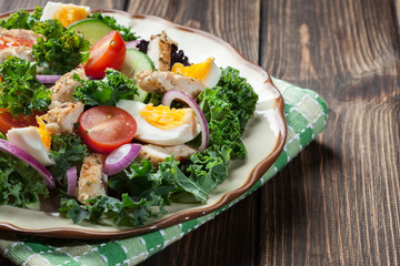 Fresh salad with chicken, tomatoes, eggs and lettuce on plate