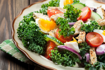 Fresh salad with chicken, tomatoes, eggs and lettuce on plate