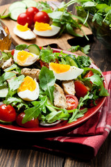 Fresh salad with chicken, tomatoes, eggs and arugula on plate