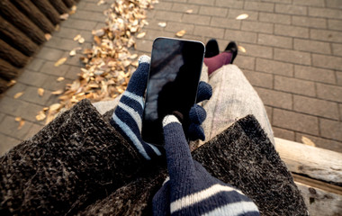 冬のベンチでスマホを操作する女性