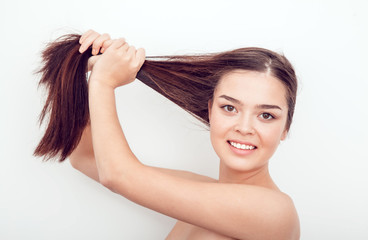 Fototapeta premium Beautiful Asian girl holds her hair in hands. Naked shoulders.