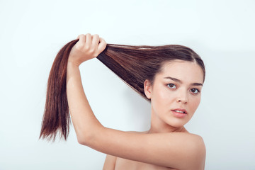 Fototapeta premium Beautiful Asian girl holds her hair in hands. Naked shoulders.