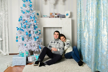Nice love couple sitting on carpet in front of fireplace