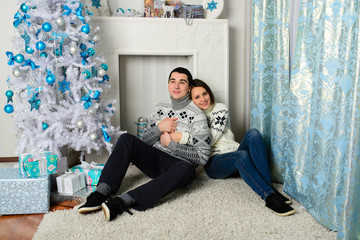 Naklejka premium Nice love couple sitting on carpet in front of fireplace