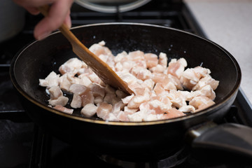 Frying cube sliced chicken meat in pan.