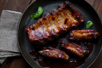 Baked pork ribs served with sauce in a frying pan, above view