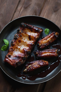 Close-up of a frying pan with baked pork ribs, studio shot
