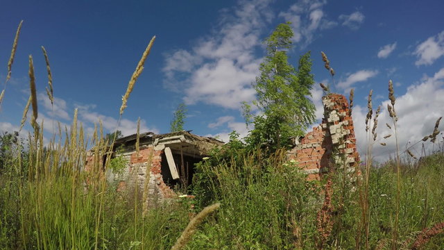 Desolate broken down brick house in the meadow on sunny summer's day with cloudy sky, 4K

