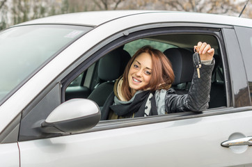 girl in the car smiling showing the keys - caucasian people