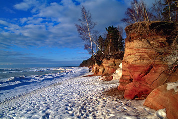 Coast of Baltic sea in Latvia. Frozen seacoast in the winter. Red sandstone cliffs at the sea. - obrazy, fototapety, plakaty
