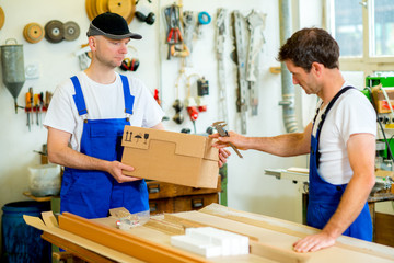 two worker with cardboard in a carpenter's workshop