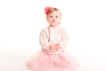Cute baby girl 1-2 year old sitting on floor over white. Looking at camera. Childhood. 