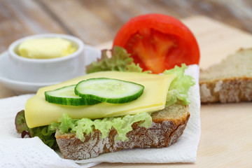 Slice of rustic rye bread with cheese lettuce and cucumber

