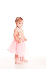 Smiling baby girl 1-2 year old standing over white. Wearing stylish skirt and pearl necklace. Looking at camera. Childhood.