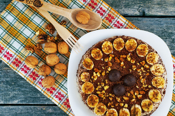 Chocolate cake with nuts and bananas on a plate and walnuts on a yellow napkin