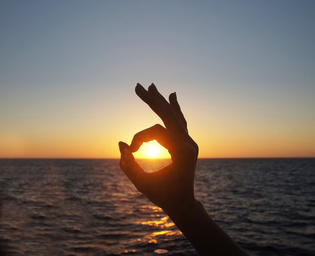 Sunset in OK hand sign on Santorini island.