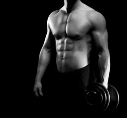 Strong, fit and sporty bodybuilder man with a dumbbell in graysc