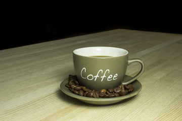Cup of coffee  with beans standing on a wooden table