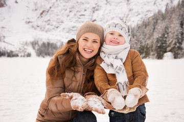 Obraz premium Mother and child showing snowy gloves in winter outdoors