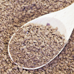 Granules of instant coffee in wooden spoon