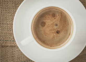 Cup of hot coffee on brown fabric