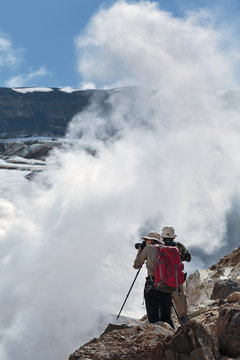 Tourists photographing smoking fumarole on crater active volcano