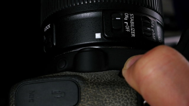 Close up of a man adjusting lens on a photo camera, 