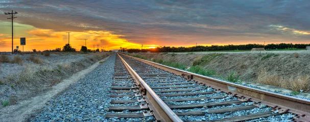 Foto op Aluminium Panoramisch zicht op spoorlijnen die het frame van rechts naar links kruisen. © motionshooter