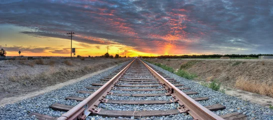 Fotobehang Panoramisch zicht op spoorlijnen die het frame van rechts naar links kruisen. © motionshooter