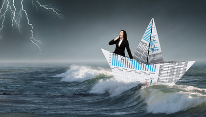 Businesswoman in boat made of paper