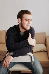 Fototapeta premium Handsome man wearing a black jacket and jeans sitting down intsi