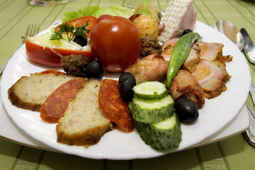 Appetizer with meat and vegetables: tomato, salami, olives, meatballs, cucumber, bell pepper, bacon, ham, cheese