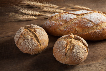 Bread and wheat ears on wooden background