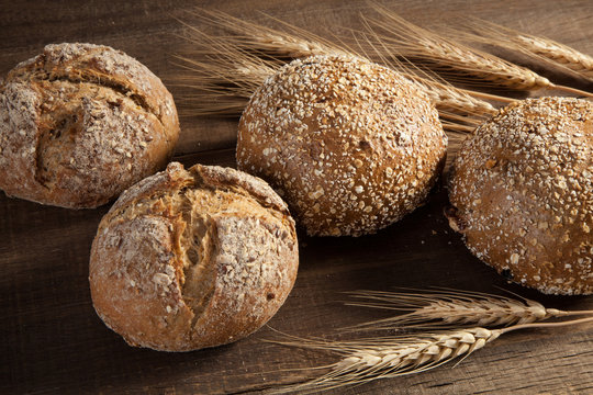 Bread and wheat ears on wooden background