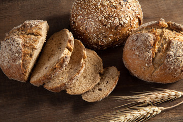 Bread and wheat ears on wooden background