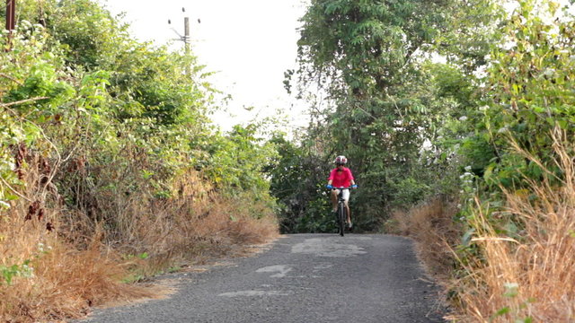 Young girl cycling along a village road in Goa, India