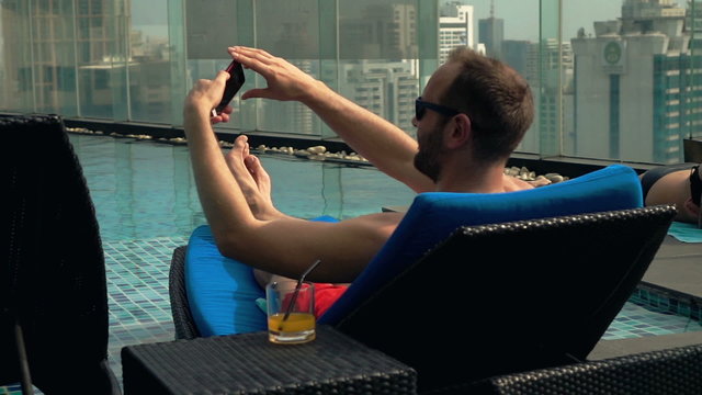 Man taking selfie photo with cellphone on sunbed, super slow motion 240fps
